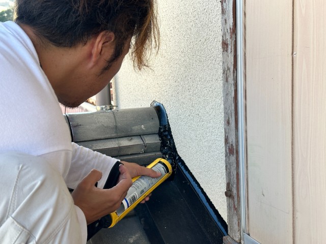 屋根と外壁が接する部分にシーリングを施工している作業