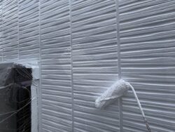 船橋市の住宅の外壁に上塗りをしている様子