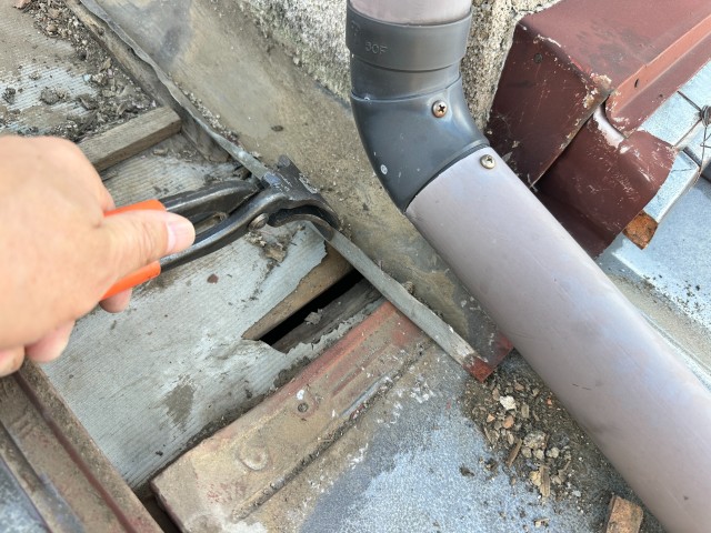 工具で捨て板金の端部を調整している作業